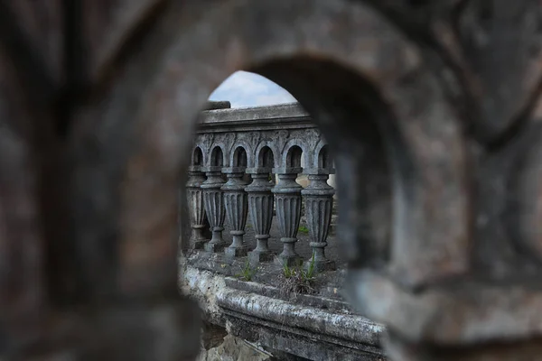 Een verwoest balkon in een oud gebouw. Betonnen oude balusters. Muur met tekenen van vernietiging, afbrokkelend pleisterwerk. Onscherp. Close-up. — Stockfoto