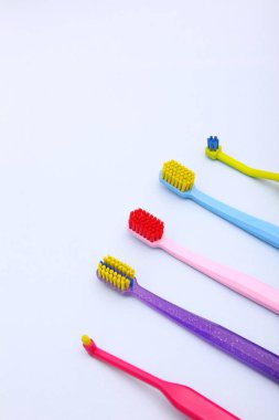 Açık arkaplanda plastik renkli diş fırçaları. Diş ve diş tellerini temizlemek için fırçalar. Diş fırçası çeşitleri. Uzayı kopyala. Yukarıdan bak. Dikey fotoğraf.