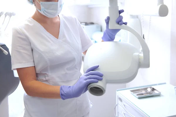 Diş hekimi, dişlerin fotoğrafını çekmek için elinde bir röntgen cihazı tutuyor. Diş hekimliğinde diş taraması. Tanınmaz halde. Eldivenli eller.