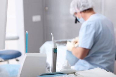 İşteki dürbünlü dişçi. Arka planda dikey bir fotoğraf. Diş implantı yerleştirme hazırlığı. Estetik dişçilik. Karaciğer ağrısı önleyici. Doktor odağını kaybetmiş. Arkaplan için fotoğraf.