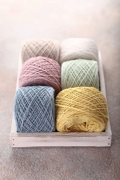 Multicolored cotton yarn for knitting lies in a wooden box. Yarn in skeins. Hobby concept. Handmade. Vertical photo.Top view.