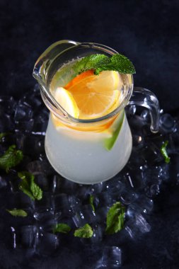 Portakallı ve naneli ev yapımı limonata. Tazeleyici içecek. Cam sürahide limonata. Dikey fotoğraf. Detoks içeceği.