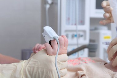 Kandaki oksijen seviyesini ölçen bir cihaz. Çocuğun parmağında nabız oksimetresi var. Çocuğu ameliyata hazırlıyorum. Bir çocuk doktor eli uzattı. Tanınmayan insanlar. Bir kaydediliyor
