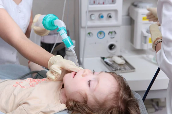 Holčička před operací. Resuscitátor drží na dětské tváři kyslíkovou masku. Celková anestezie. Záchrana života. Umělé plicní ventilační přístroje. — Stock fotografie