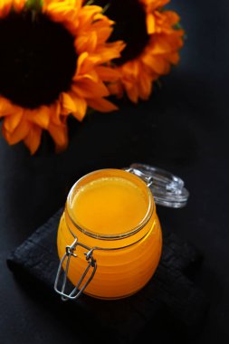 Siyah arka planda ballı cam kavanoz. Sıvı bal. Ayçiçeği. Biyolojik ürün. Dikey fotoğraf. Bal için cam çubuk. Yukarıdan bak. Boşluğu kopyala.
