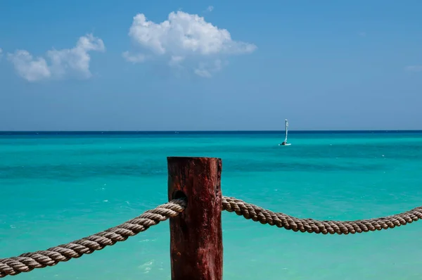 Rustikální Lano Dřevěnou Opěrnou Tyčí Pozadí Karibské Moře Malou Plachetnicí — Stock fotografie
