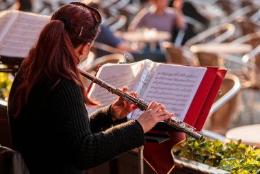 Tanınmayan müzisyen Venedik, İtalya 'daki Piazza San Marco' da bir açık hava barında flüt çalıyor. Arka planda müzik müziği var.