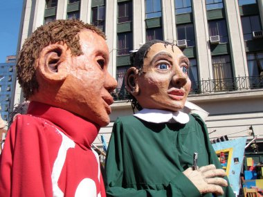 Dev karnaval karakterleri Şili 'nin Valparaiso şehrinin sokaklarında geçit yapıyor. Arka planda yakınlardaki binaların pencereleri.