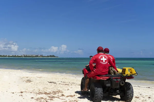 Dörtlü bisikletteki iki cankurtaran sahili ve banyoyu izlemek için okyanusu gözlüyor. Meksika 'da tatil ve koruma kavramı