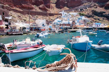 Yunanistan 'ın Santorini adasındaki küçük Amoudi limanının körfez ve tekneleriyle manzarası. Arka planda köyün evleri volkanın kalderasının önünde..