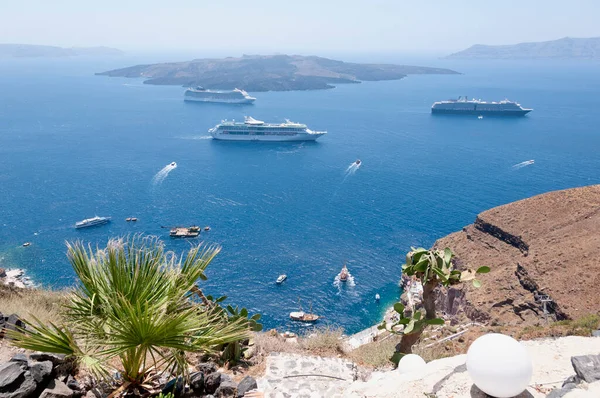 Santorini adasındaki volkanın kalderasının hava panoramik görüntüsü yolcu gemileriyle birlikte. Arka planda mavi gökyüzü ve Ege Denizi