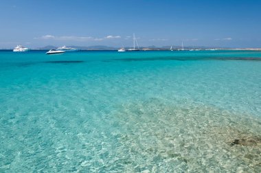 Ses Illetes plajının panoramik manzarası, Formentera, İspanya. Arka planda demirli lüks tekneler. Konsept seyahat ve turizm