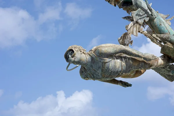 Meksika 'nın Cozumel adasında mavi bir zemine karşı bir dalgıcın bronz heykeli.