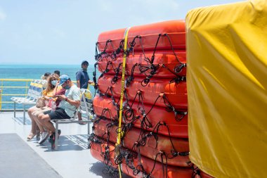 Bir grup insan Meksika 'daki bir feribotun can kurtaran botunun yanında oturuyor. Seçici odak, nakliye güvenliği, deniz güvenliği.