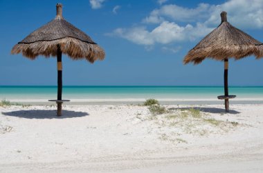 İki hasır şemsiyesi olan tropik bir plaj. Tatil konsepti Holbox, Meksika 'daki tropikal plaj adası