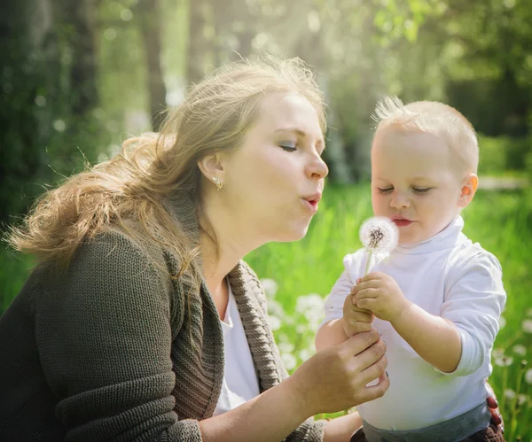 Madre e hijo soplando en un diente de león — Foto de Stock