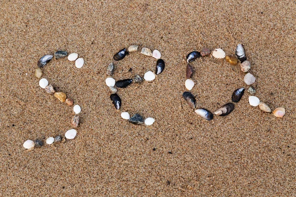 Word sea made of shells and pebbles on the sand — Stock Photo, Image