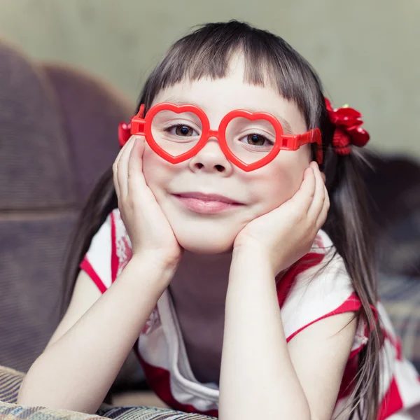 Preciosa niña sonriente en gafas en forma de corazón —  Fotos de Stock