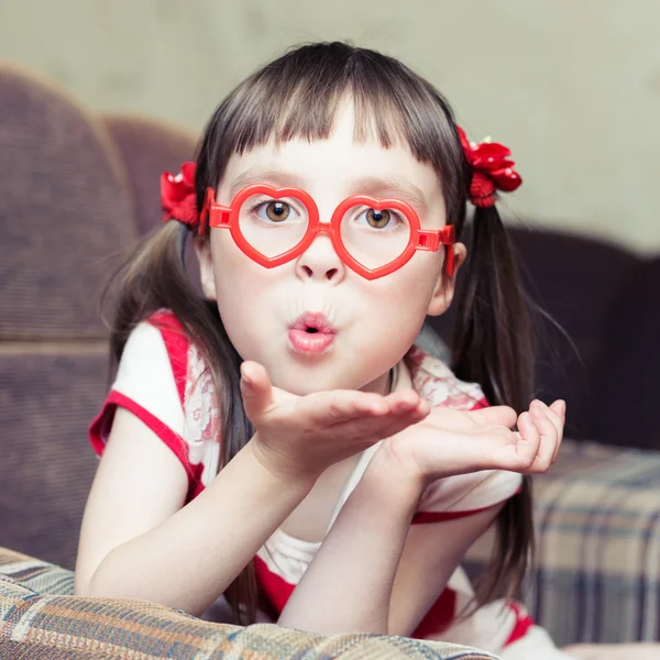 Linda niña con gafas en forma de corazón envía un beso de aire —  Fotos de Stock