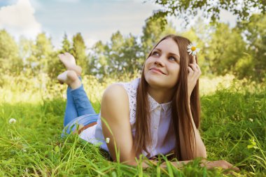 Güzel kız çayır üzerinde papatya çiçeği ile saçında yatıyor