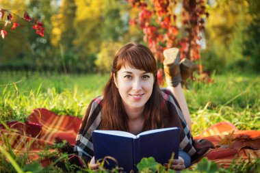 Kameraya bakarak bir kitapla sonbahar parkta güzel kız