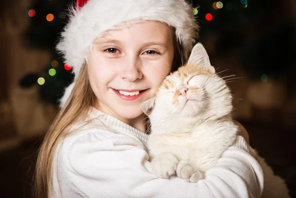 Милая маленькая девочка обнимает свою кошку на Рождество — стоковое фото