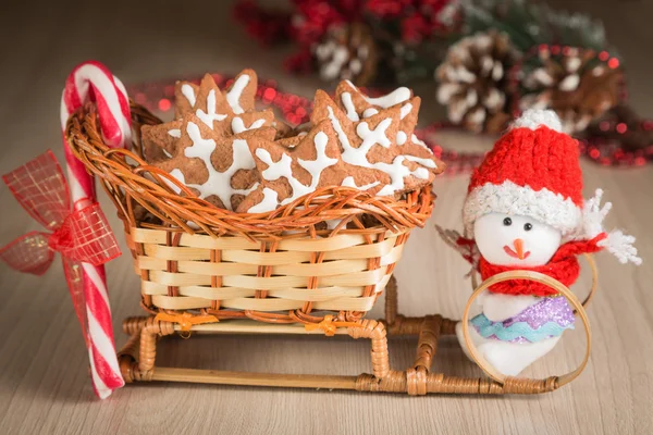 Gift basket-sleigh with cookies, candy and a toy snowman dressed in warm clothes