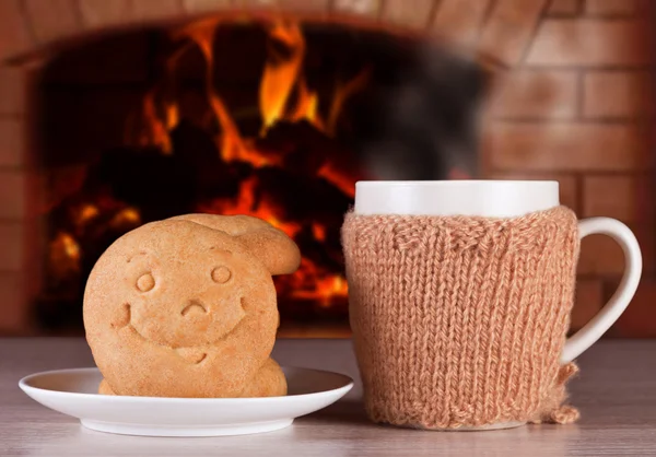 Minuman panas dengan roti dalam bentuk senyum untuk suasana hati yang hangat dan positif di latar belakang api yang menyala-nyala dalam oven — Stok Foto