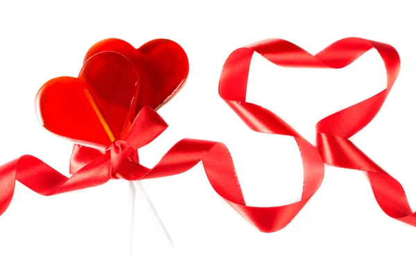 Symbol Valentinstag: Lutscher in Herzform, zugehöriges Band und Herz aus gedrehten Bändern — Stockfoto