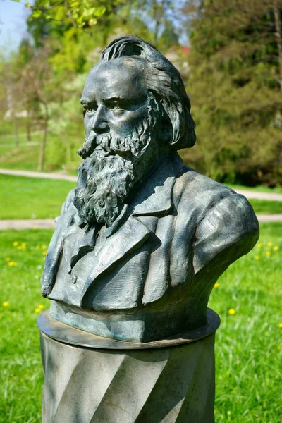 Almanya 'da bir halk parkında Alman besteci Johannes Brahms' ın büstündeki güneş ışığı. Arkaplanda yeşil bitki örtüsü.