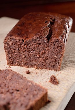 Tahta kesme tahtasının üzerinde ahşap hindistan cevizli çikolatalı kek. Yakın plan, koyu arkaplan.