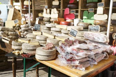 Sosis, jambon, Saint-Nectaire peyniri, Tomme peyniri, ekmek ve diğer yerel ürünlerin sergilendiği bir Fransız pazarına yakın plan. Boussac kasabası, Creuse bölümü, Yeni Aquitaine, Fransa.