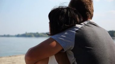 Kumsalda tahta kütüğün üzerinde otururken mutlu çift kucaklaşması. Güneşli bir günde deniz manzarasına hayran olan romantik bir çift. Sevgililer tatil köyünde birlikte vakit geçirirler. Yaz tatili ya da tatil kavramı. Yavaş çekim