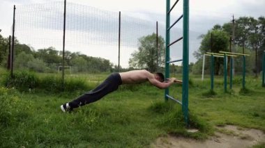 Spor malzemelerinde trisepsler üzerinde egzersiz yapan genç kaslı bir atlet. Spor sahasında spor yapan erkek üstsüz sporcu. Doğada güçlü bir sporcu eğitimi. Sağlıklı yaşam tarzı kavramı.