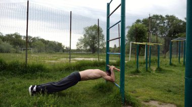 Spor malzemelerinde trisepsler üzerinde egzersiz yapan genç kaslı bir atlet. Spor alanında spor yapan erkek üstsüz bir sporcu. Doğada güçlü bir sporcu eğitimi. Sağlıklı yaşam tarzı kavramı.