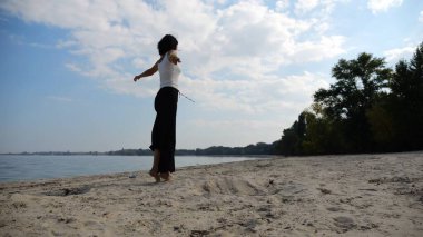 Güneşli bir günde sahil kenarında kumsalda yürüyen güzel bir bayan. Mutlu yetişkin kadın kıyı şeridine doğru dönüyor. Kaygısız kadın deniz kenarında dinleniyor. Yaz tatili veya tatil kavramı