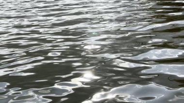 Yazın güneşle aydınlatılan göletin manzara yüzeyi. Güneşli bir günde deniz manzarası ve küçük dalgalar. Güzel yaz doğa manzarası. Huzur sahnesi kavramı. Yavaş çekim