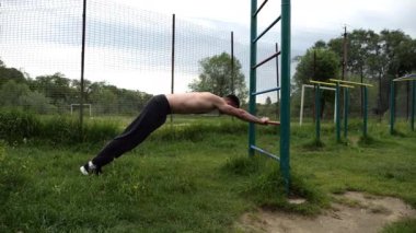 Spor malzemelerinde trisepsler üzerinde egzersiz yapan genç kaslı bir atlet. Spor alanında spor yapan erkek üstsüz bir sporcu. Doğada güçlü bir sporcu eğitimi. Sağlıklı yaşam tarzı kavramı.