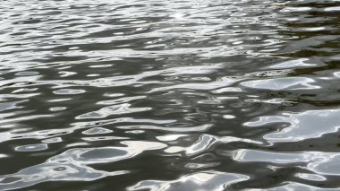 Yazın güneşle aydınlatılan göletin manzara yüzeyi. Güneşli bir günde deniz manzarası ve küçük dalgalar. Güzel yaz doğa manzarası. Huzur sahnesi kavramı. Yavaş çekim