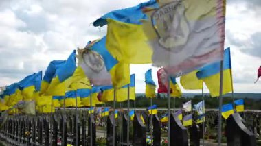 View on blue-yellow flags at countless graves of ukrainian soldiers alley of glory in Kharkiv. This site commemorates heroes and maintains the memory of wartime events in Ukraine. Slow mo