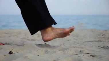 Deniz kıyısında yürüyen yetişkin kadın bacakları. Sahilde kumsalda arka planda deniz manzarası olan kadın ayakları. Çıplak ayaklı kadın okyanus kıyısında geziniyor. Yaz tatili kavramı.