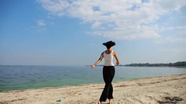 Güneşli bir günde sahilde koşan mutlu yetişkin kadın. Arka planda sakin dalgalarla deniz kıyısında koşan güzel bir bayan. Yaz tatili ya da tatil kavramı. Yavaş çekim