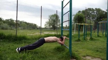 Spor malzemelerinde trisepsler üzerinde egzersiz yapan genç kaslı bir atlet. Spor sahasında spor yapan erkek üstsüz sporcu. Doğada güçlü bir sporcu eğitimi. Sağlıklı yaşam tarzı kavramı.