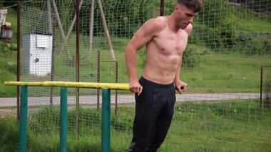 Genç sporcu doğada paralel barlarda şınav çekiyor. Spor alanında egzersiz yapan güçlü bir sporcu. Erkek üstsüz sporcu dışarıda sıkı çalışıyor. Aktif spor yaşam tarzı kavramı. Yavaş çekim
