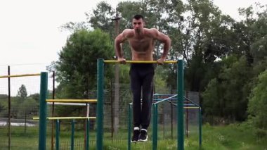 Cesur üstsüz sporcu doğada yatay çıtada şınav çekiyor. Güçlü ve kaslı adam spor alanında antrenman yapıyor. Genç atletik adam dışarıda egzersiz yapıyor. Aktif ve sağlıklı yaşam tarzı kavramı.