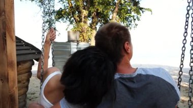 Romantik çift deniz sahilinde salıncakta sallanıyor. Mutlu aşıklar tatil köyünde birlikte vakit geçirmeyi severler. Kaygısız bir çift güneşli bir günde okyanusun kenarında dinleniyor. Yaz tatili veya tatil kavramı.