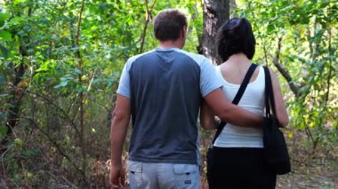 Mutlu çift yaz ormanında yolda yürüyor. Vahşi ormanlık alanda romantik bir çift geziyor. Sevgililer doğada birlikte vakit geçirirler. Aşk ve mutluluk kavramı. Yavaş çekim
