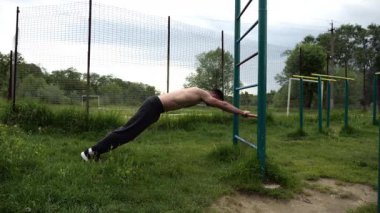 Spor malzemelerinde trisepsler üzerinde egzersiz yapan genç kaslı bir atlet. Spor alanında spor yapan erkek üstsüz bir sporcu. Doğada güçlü bir sporcu eğitimi. Sağlıklı yaşam tarzı kavramı.