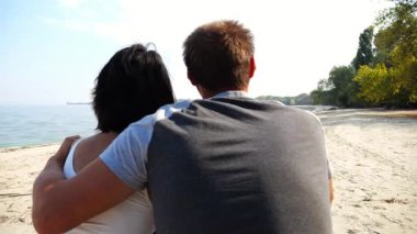 Kumsalda tahta kütüğün üzerinde otururken mutlu çift kucaklaşması. Güneşli bir günde deniz manzarasına hayran olan romantik bir çift. Sevgililer tatil köyünde birlikte vakit geçirirler. Yaz tatili ya da tatil kavramı. Yavaş çekim