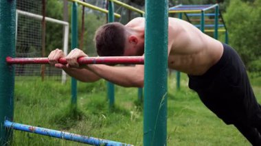 Spor malzemelerinde trisepsler üzerinde egzersiz yapan genç kaslı bir atlet. Spor alanında spor yapan erkek üstsüz bir sporcu. Doğada güçlü bir sporcu eğitimi. Sağlıklı yaşam tarzı kavramı.